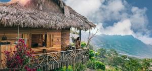 a wooden house with a thatched roof on a mountain at Khu sinh thái Ecolodge Kê Nênh Điện Biên in Ban Hin Lom