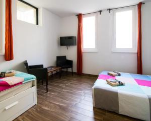 a room with two beds and a desk and a tv at Sobe Argo Izola in Izola