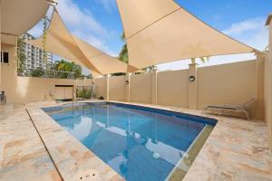 una piscina con ombrellone in cima a un edificio di Baywatch Escape - Beachside Living near Darwin CBD a Larrakeyah