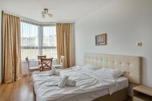 sypialnia z dużym białym łóżkiem i oknem w obiekcie Kabakum Plaza Beachfront flats w Warnie +36 zdjęć