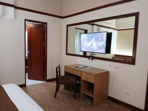 ein Hotelzimmer mit Schreibtisch und Spiegel in der Unterkunft Dohera Hotel in Cebu City
