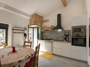 una cucina con mobili bianchi e un tavolo con sala da pranzo di Gîte de charme 18ème avec spa et terrasse, St-Julien-Molin-Molette - FR-1-496-335 a Saint-Julien-Molin-Molette Altre 12 foto