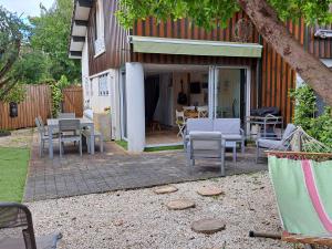 un patio con sedie e tavoli in un cortile posteriore di Maison de vacances climatisée avec JACUZZI proche du Lac - FR-1-831-12 a Biscarrosse
