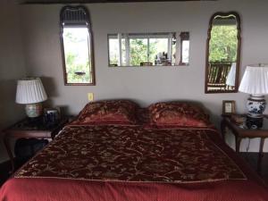 a bedroom with a large red bed with two windows at Hacienda las Nubes in Turrialba