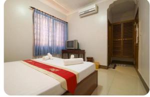a bedroom with a bed and a television in it at UCS GUESt HOUSE in Siem Reap