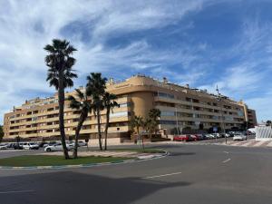 a large building with palm trees in a parking lot at Ático Roquetas in Roquetas de Mar