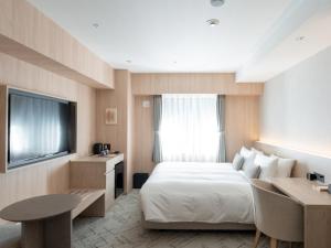 a hotel room with a bed and a desk and a television at HOTEL THE LEBEN OSAKA in Osaka