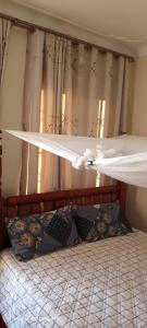 a bed in a bedroom with a window with curtains at Rogerzi in Bwerenga +7 photos