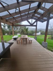 une terrasse en bois avec une table et des bancs sous une pergola dans l'établissement Orira River Cottage, à Umawera