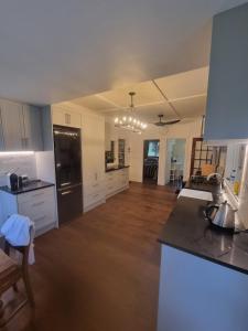 une cuisine avec des armoires blanches et un réfrigérateur noir dans l'établissement Orira River Cottage, à Umawera