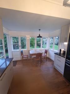 une cuisine avec une table, des chaises et des fenêtres dans l'établissement Orira River Cottage, à Umawera 3 autres photos