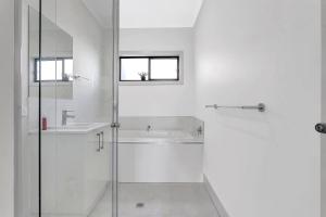 a white bathroom with a shower and a sink at Modern Coastal Retreat in Aldinga Beach Just Steps from the Shore in Aldinga Beach +7 photos