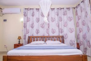 ein Schlafzimmer mit einem Bett mit einem lila-weißen Vorhang in der Unterkunft Modern Apartments Nyali in Mombasa + 9 Fotos