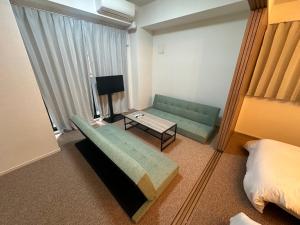 Una sala de estar con un sofá verde y una mesa. en APATEL Shinsaibashi, en Osaka