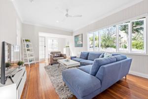 a living room with a blue couch and a tv at Charming Cottage Short Distance to CBD with Parking in Brisbane