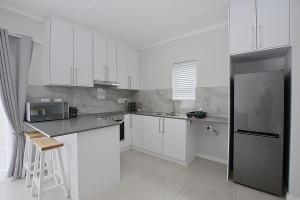 a kitchen with white cabinets and a stainless steel refrigerator at Apartment 2-bedroom #3 Leetch Views in Cape Town