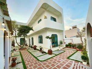 a large white house with a courtyard with potted plants at Phú Quý MYNO Homestay in Cu Lao Thu