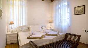 ein weißes Bett in einem Zimmer mit einem Stuhl und einem Fenster in der Unterkunft Ontas Traditional Hotel in Chania