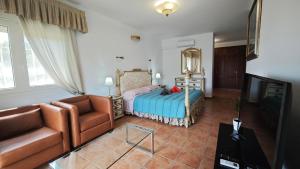 a bedroom with a bed and a couch and a television at Rooms Flor del Pato in Benalmádena