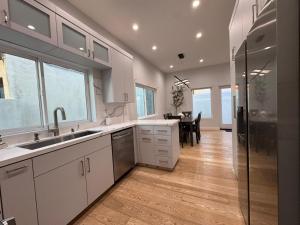a kitchen with white cabinets and a dining room at Newly constructed 2 bedroom by La Cienega Plaza with parking, modern kitchen, washer dryer and very central to attractions in Los Angeles