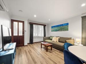 una sala de estar con un sofá y una mesa en Marguerite Studio - central town & pool, en Margaret River Town