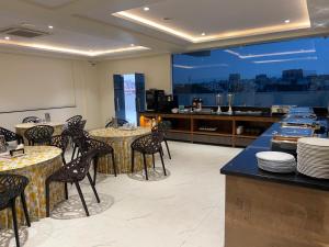 a restaurant with tables and chairs and a kitchen at Hotel Lemon Park in Visakhapatnam