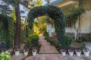 a garden with an arch and potted plants at Boutique Villa w Bonfire & BBQ, Mussoorie Foothills in Dehradun +46 photos
