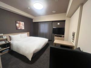 宇部にあるホテルルートイン宇部のベッドとテレビがあるホテルの部屋