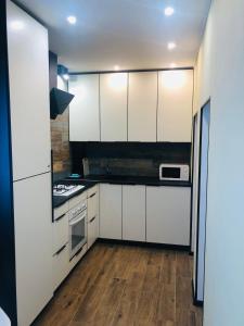 a kitchen with white cabinets and a stove at Cozy apartment near the center in Vinnytsya