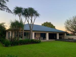 een huis met palmbomen voor een tuin bij April House in Howick