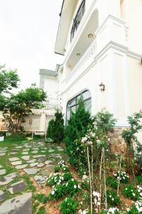 a garden in front of a white building at Cerasoi Boutique Dalat Hotel in Da Lat +31 photos