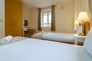 a hotel room with two beds and a window at Gort Na Coiribe - Galway Lakeside Apartments in Galway
