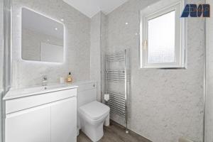 a bathroom with a toilet and a sink and a window at 3BR Home in Kilmarnock Sleeps 6 in Kilmarnock
