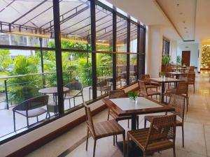 ein Restaurant mit Tischen und Stühlen und großen Fenstern in der Unterkunft Dohera Hotel in Cebu City