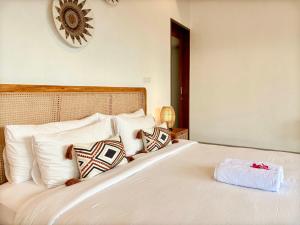 a white bed with pillows and a clock on the wall at Obah Villa Ubud 1 Br Brand new private villa in Ubud