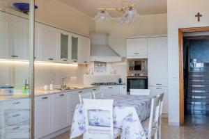 a kitchen with white cabinets and a table and chairs at Casa Maggio in Roccalumera