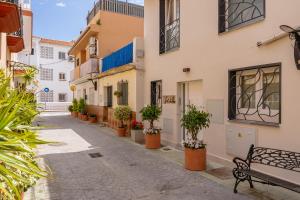 a street with potted plants and a bench at Cala Sol - few steps from the beach in La Cala de Mijas