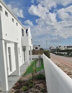 a white house with a white fence and a road at Skye in Paternoster +5 photos