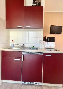 a kitchen with red cabinets and a sink at Küstenkoje Red Balkon und Hund willkommen in Prerow