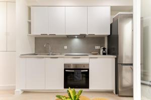a kitchen with white cabinets and a stainless steel refrigerator at Cala Azul-few steps from the beach in La Cala de Mijas