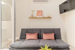 a gray couch with two pink pillows in a room at Cala Azul-few steps from the beach in La Cala de Mijas