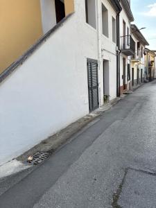 an empty street with a white building and a door at Casa Mia in Alife
