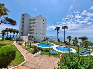 ein Gebäude mit zwei Pools und Palmen und dem Meer in der Unterkunft ALGAIDA BEACHFRONT CALAHONDA MIJAS near MARBELLA in Mijas Costa