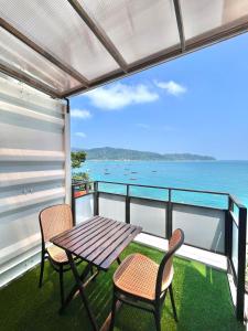 a table and chairs on a balcony with the ocean at Perhentian Nemo Chalet in Perhentian Island
