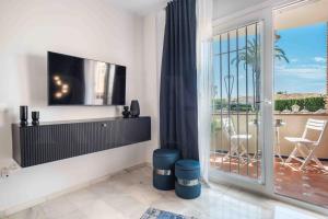 a living room with a television and a balcony at Sunny apartment with balcony & swimming pool by REMS in Sitio de Calahonda