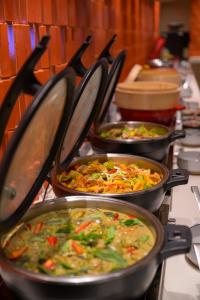 una fila de sartenes llenas de diferentes tipos de alimentos en Centara Karon Resort Phuket, en Karon Beach