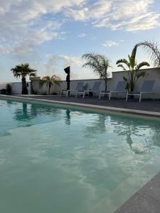 a large swimming pool with chairs and palm trees at VISTAMARE beach garden relax in San Leone