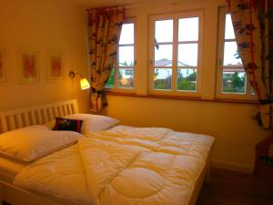 a bedroom with a bed and two windows at App Nixe mit WLAN und Kamin Haustiere Willkommen in Börgerende-Rethwisch