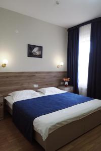 Un dormitorio con una cama grande con una manta azul. en Asia Hotel, en Bishkek