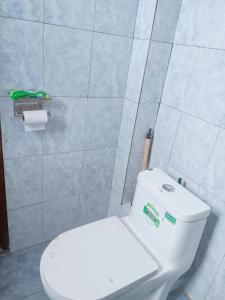 a bathroom with a white toilet and a roll of toilet paper at Blue-orchid House in Nairobi